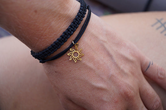Schwarzes Makramee Armband-Duo mit Sonnenanhänger auf gebräunter Haurt