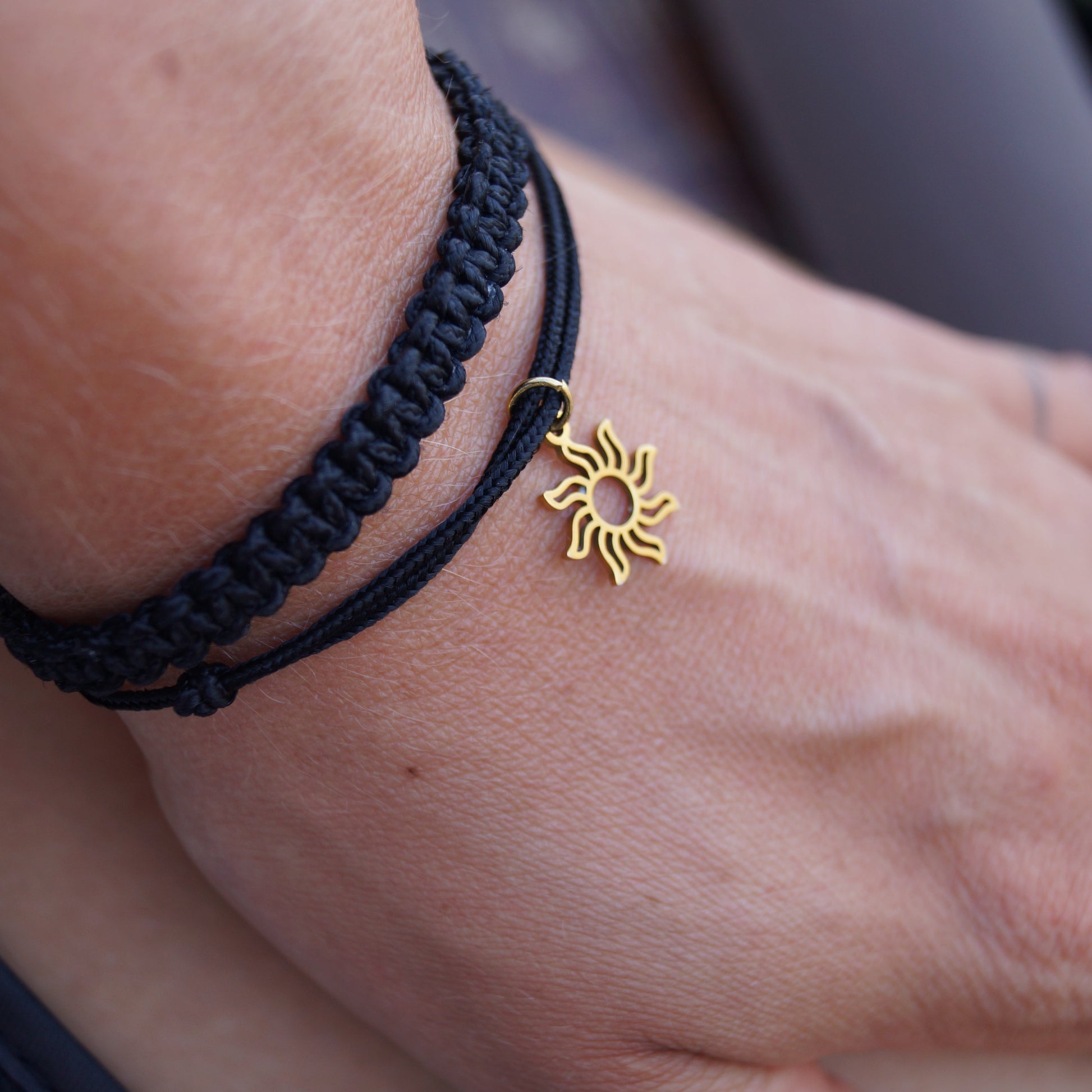 Schwarzes Makramee Armband-Duo mit Sonnenanhänger auf gebräunter Haurt