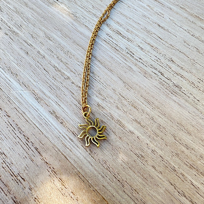 Zarte goldfarbene Sonnen Kette aus Edelstahl auf hellem Untergrund.