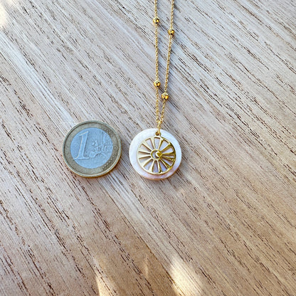 Goldfarbene Edelstahl Halskette mit rundem Perlmutt Sonne-Mond Anhänger neben einer 1-Euro-Münze zum Größenvergleich.