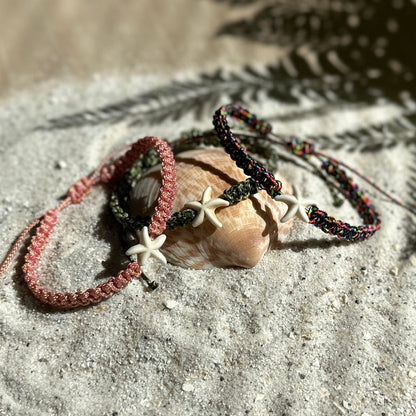 Seestern-Fußkettchen in 3 verschiedenen Farben auf einer Muschel und weißem Sand mit Palmblatt Schatten