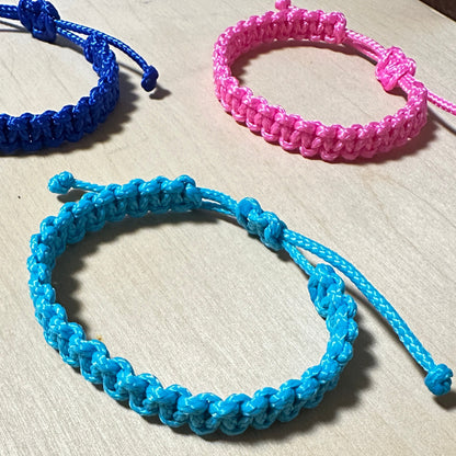 Segeltau Armbänder in den 3 Farben türkis, neonpink und lau auf einer hellen Tischplatte. 