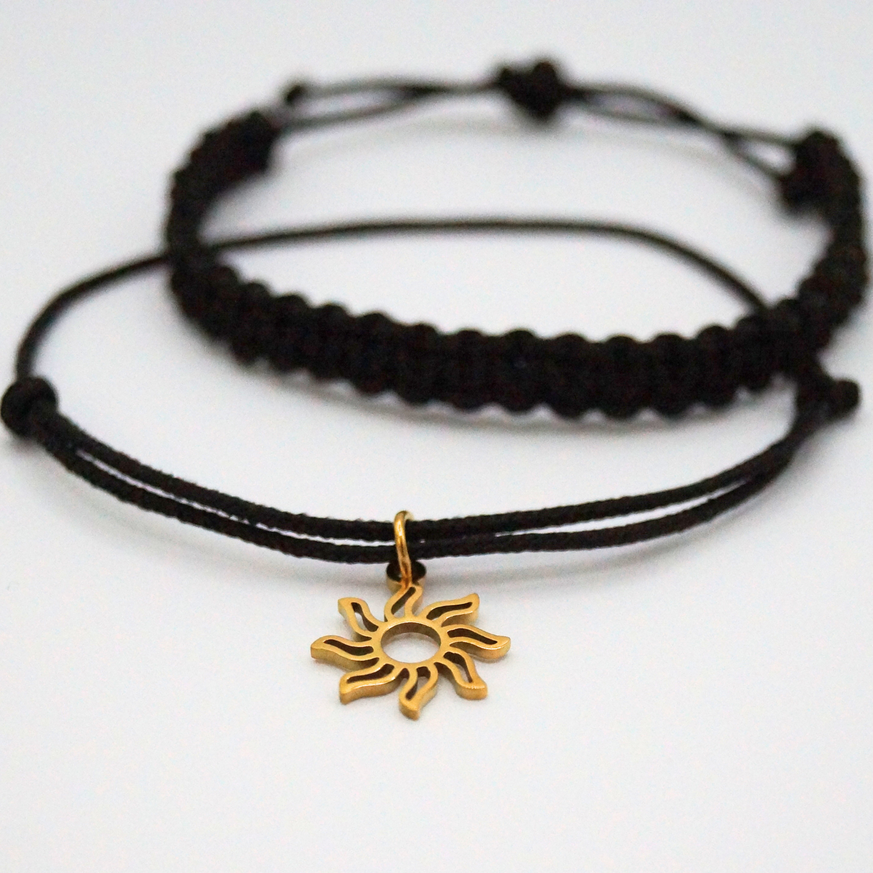 Detailansicht eines Armband-Duos in schwarz mit goldfarbenem Sonnenanhänger