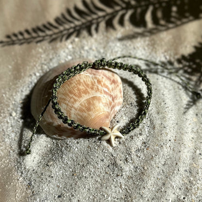 Seestern-Fußkettchen in Camouflage auf einer Muschel und weißem Sand mit Palmblatt Schatten