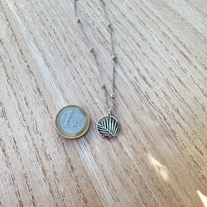 Silberne Palmblatt Halskette aus Edelstahl im Größenvergleich neben einer 1-Euro-Münze.